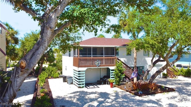 view of front of property with a garage, a sunroom, driveway, and stairway