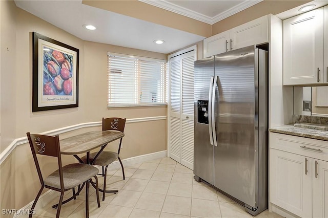 kitchen featuring stainless steel fridge, white cabinetry, ornamental molding, and light stone counters