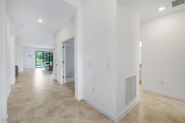 hall featuring visible vents, baseboards, and light tile patterned flooring