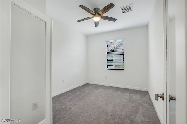 carpeted spare room with ceiling fan, visible vents, and baseboards