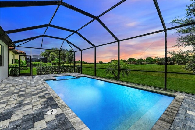 pool at dusk with glass enclosure and a patio area