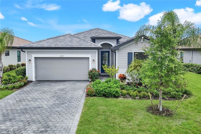 single story home with an attached garage, a front lawn, and decorative driveway