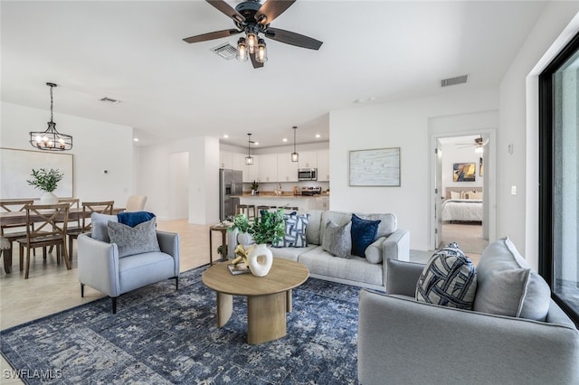 living room with ceiling fan with notable chandelier