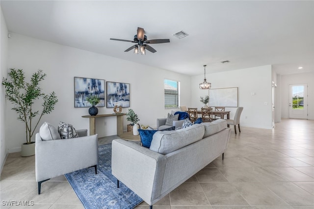 living area with light tile patterned floors, ceiling fan, visible vents, and baseboards