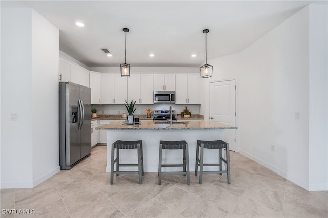 kitchen with stainless steel appliances, white cabinets, a sink, and a breakfast bar area