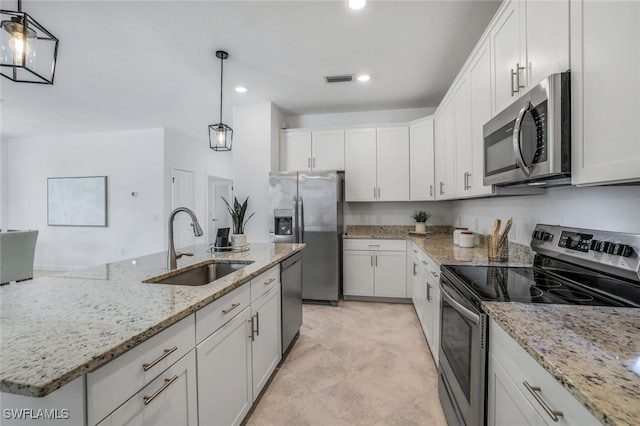 kitchen with appliances with stainless steel finishes, white cabinetry, a sink, and hanging light fixtures