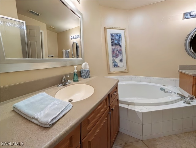 bathroom with tiled bath, tile patterned floors, and vanity