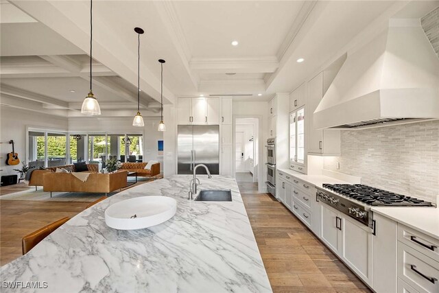 kitchen with beam ceiling, light stone countertops, premium range hood, and stainless steel appliances