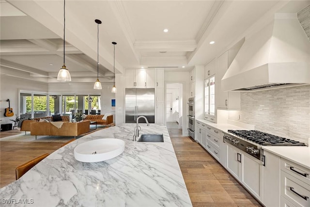 661 6th Ave N, Naples, FL 34102 - kitchen with stainless steel appliances, wall chimney exhaust hood, open floor plan, decorative backsplash, and white cabinets