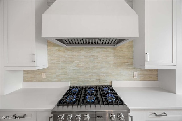 kitchen with decorative backsplash, stove, white cabinets, and custom range hood