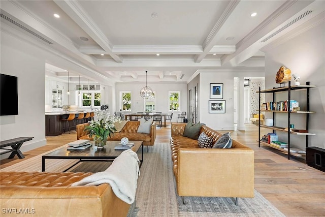 living room featuring beamed ceiling, light hardwood / wood-style floors, ornamental molding, and a chandelier