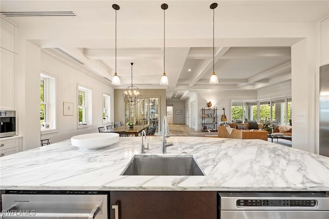 kitchen featuring pendant lighting, sink, light stone countertops, beamed ceiling, and a notable chandelier