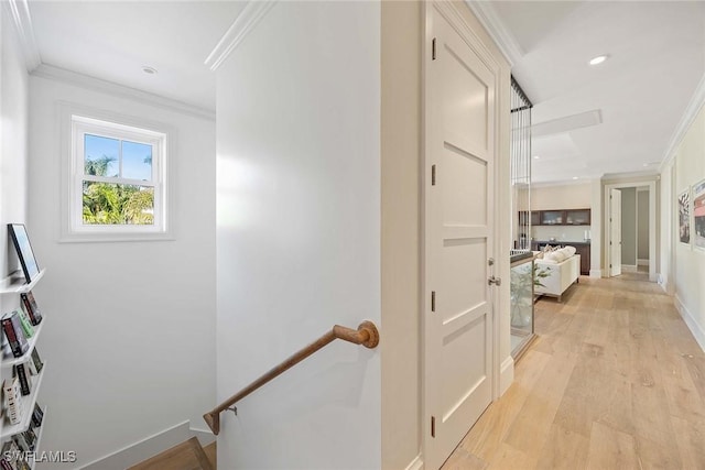 hallway with light wood-type flooring and ornamental molding