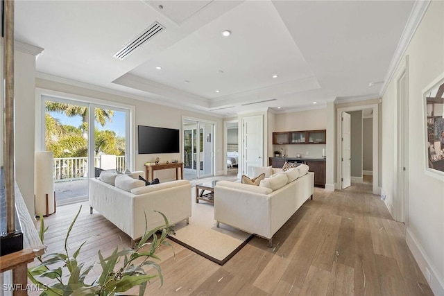 living room featuring a tray ceiling, light hardwood / wood-style flooring, and ornamental molding