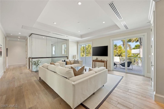 living room featuring a raised ceiling, crown molding, and light hardwood / wood-style floors