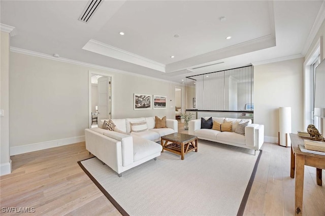 living room with a tray ceiling, light hardwood / wood-style flooring, and crown molding