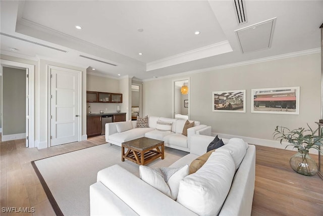 living room with light hardwood / wood-style flooring, a raised ceiling, crown molding, and sink