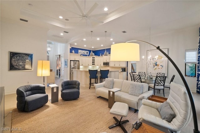 living room featuring a raised ceiling, ceiling fan with notable chandelier, and ornamental molding