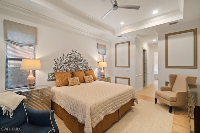 bedroom featuring light wood-type flooring, a tray ceiling, ceiling fan, and crown molding