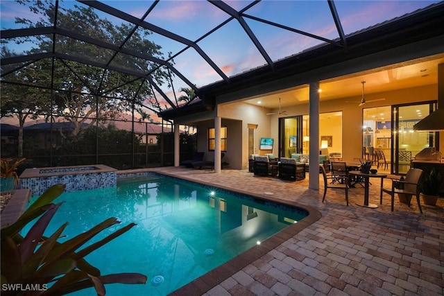 pool at dusk featuring an in ground hot tub, an outdoor hangout area, ceiling fan, glass enclosure, and a patio