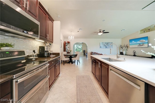 kitchen with backsplash, sink, stainless steel appliances, and ceiling fan with notable chandelier