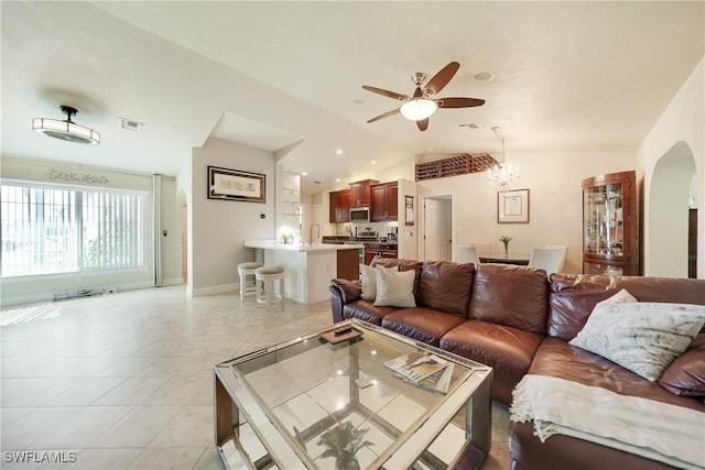 tiled living room featuring ceiling fan with notable chandelier and lofted ceiling