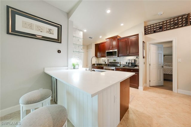 kitchen with a kitchen bar, appliances with stainless steel finishes, tasteful backsplash, sink, and lofted ceiling