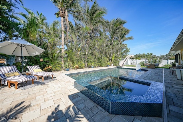 view of pool with a patio area, an in ground hot tub, and a water slide