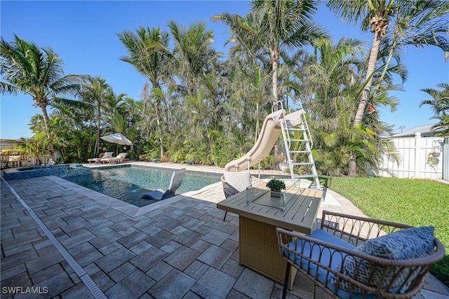 view of swimming pool featuring a yard, a patio, and a water slide