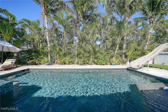 view of swimming pool with a water slide and a patio