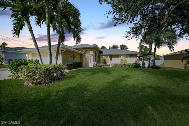 ranch-style house featuring a garage and a lawn