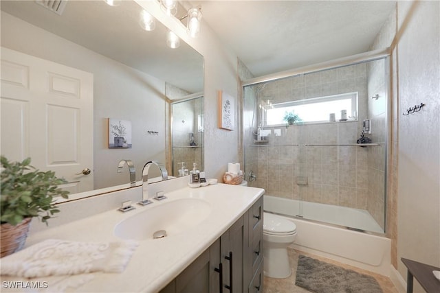 full bathroom featuring tile patterned floors, vanity, toilet, and bath / shower combo with glass door