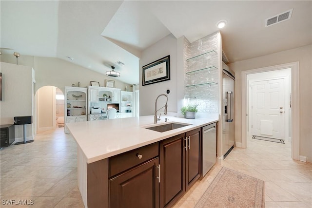 kitchen with dishwasher, lofted ceiling, a kitchen island with sink, sink, and dark brown cabinets