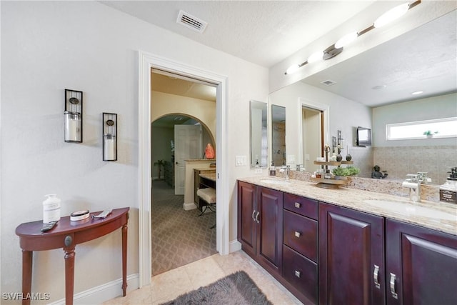 bathroom with tile patterned flooring, vanity, and a textured ceiling