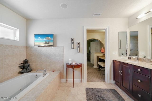 bathroom featuring tile patterned floors, vanity, and a relaxing tiled tub