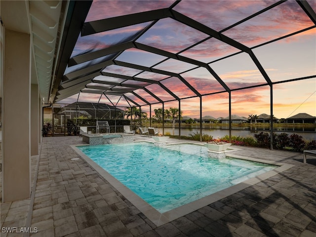 pool at dusk featuring a patio, a water view, and glass enclosure