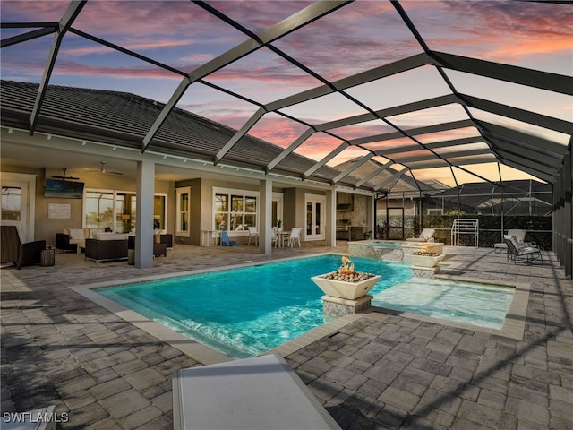 view of pool with an in ground hot tub, outdoor lounge area, ceiling fan, glass enclosure, and a patio area