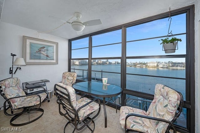 sunroom / solarium featuring ceiling fan and a water view