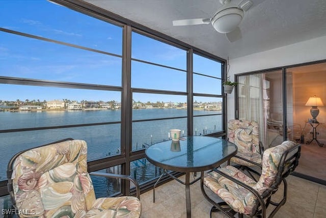 sunroom / solarium featuring a water view and ceiling fan