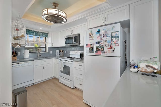 kitchen featuring white cabinetry, white appliances, a tray ceiling, and sink