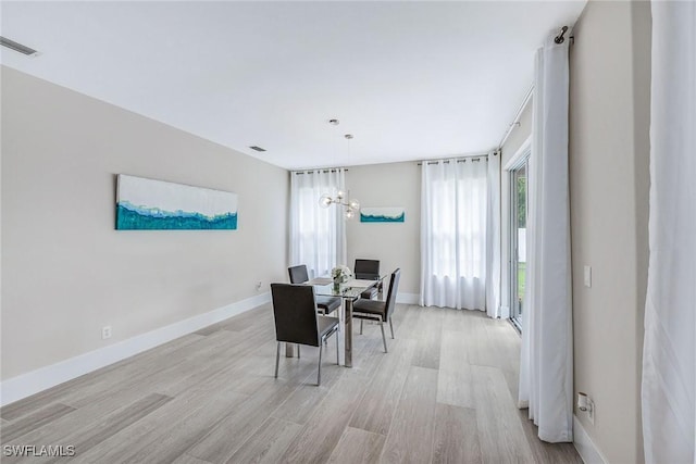 dining space featuring light hardwood / wood-style floors and an inviting chandelier