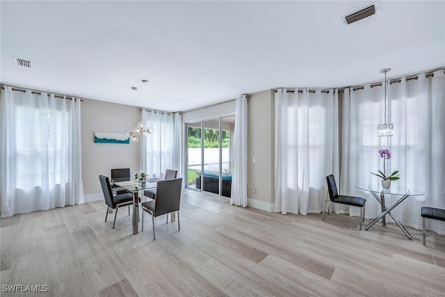 dining area with a notable chandelier and light hardwood / wood-style flooring