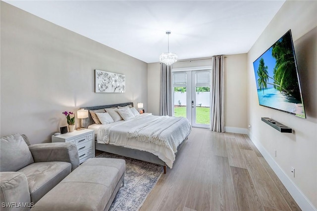 bedroom with access to outside, french doors, an inviting chandelier, and light wood-type flooring