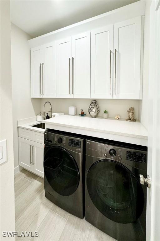 washroom featuring washer and clothes dryer, cabinets, and sink