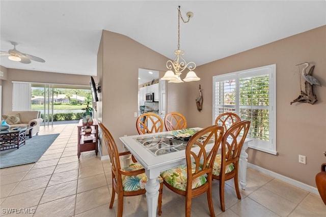 tiled dining space featuring ceiling fan with notable chandelier and vaulted ceiling