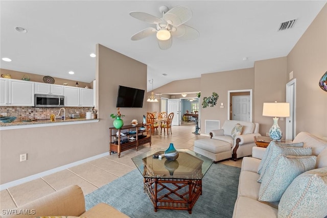 living room with ceiling fan, light tile patterned floors, and vaulted ceiling