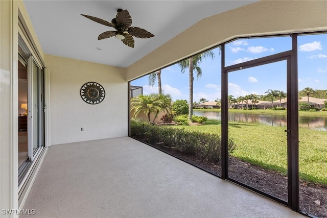 unfurnished sunroom with ceiling fan and a water view