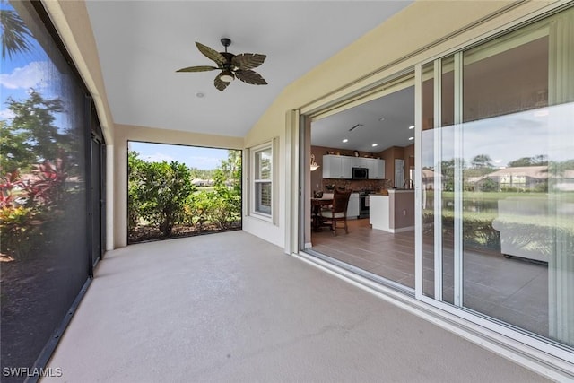 unfurnished sunroom with ceiling fan and vaulted ceiling