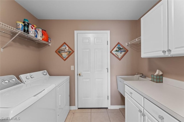 clothes washing area with cabinets, sink, light tile patterned floors, and washer and dryer