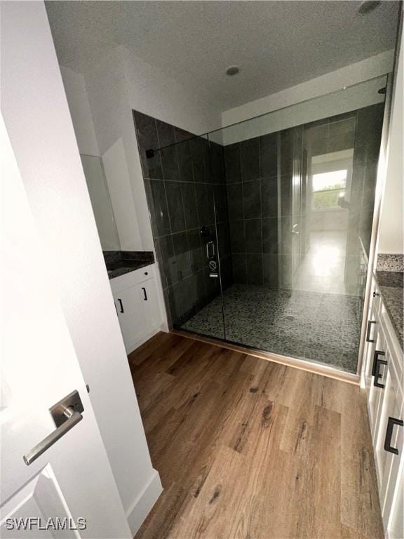 bathroom with hardwood / wood-style floors, vanity, and a shower with door